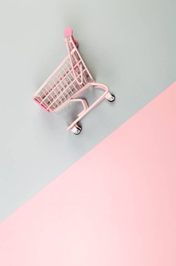 Renkli arka planda pembe alışveriş arabasının üst görüntüsü. Yaratıcı alışveriş duvar kâğıdı, satış. Uzayı kopyala, düz yat.