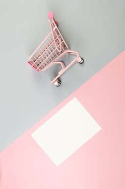 Renkli arka planda pembe alışveriş arabasının üst görüntüsü. Yaratıcı duvar kâğıdı, beyaz kart, indirim. Uzayı kopyala, düz yat.