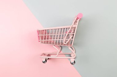 Renkli arka planda pembe alışveriş arabasının üst görüntüsü. Yaratıcı alışveriş duvar kâğıdı, satış. Uzayı kopyala, düz yat.