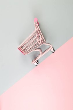 Renkli arka planda pembe alışveriş arabasının üst görüntüsü. Yaratıcı alışveriş duvar kâğıdı, satış. Uzayı kopyala, düz yat.