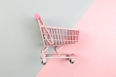 Renkli arka planda pembe alışveriş arabasının üst görüntüsü. Yaratıcı alışveriş duvar kâğıdı, satış. Uzayı kopyala, düz yat.