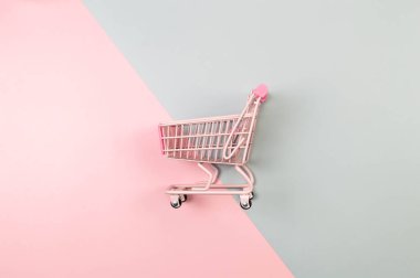 Renkli arka planda pembe alışveriş arabasının üst görüntüsü. Yaratıcı alışveriş duvar kâğıdı, satış. Uzayı kopyala, düz yat.