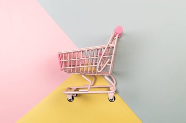Renkli arka planda pembe alışveriş arabasının üst görüntüsü. Yaratıcı alışveriş duvar kâğıdı, satış. Uzayı kopyala, düz yat.