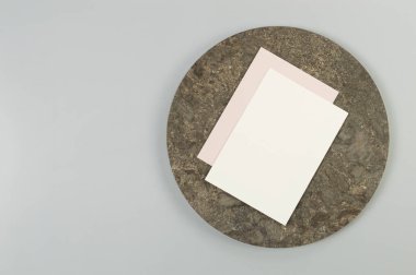 Kahverengi mermer plakanın üst görüntüsü, gri arka planda beyaz ve pembe kartlar. Yemek sunumu, taş tepsi. Uzayı kopyala, düz yat.