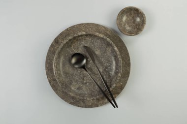 Kahverengi mermer tepsi ve tabağın üst görüntüsü, gri arkaplanda siyah çatal bıçak takımı. Yemek sunumu, taş tepsi. Tablo ayarı, kopyalama alanı, düz uzanma.