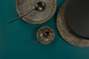 Kahverengi mermer tepsi, kase, siyah tabak ve koyu yeşil arka planda çatal bıçak. Yemek sunumu, tabaklar, taş tepsi. Uzayı kopyala, düz yat.