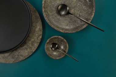 Kahverengi mermer tepsi, kase, siyah tabak ve koyu yeşil arka planda çatal bıçak. Yemek sunumu, tabaklar, taş tepsi. Uzayı kopyala, düz yat.