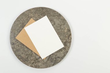 Kahverengi mermer plakanın üst görüntüsü, beyaz mermer arka planda beyaz ve kahverengi kartlar. Yemek sunumu, taş tepsi. Uzayı kopyala, düz yat.