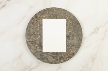 Kahverengi mermer plakanın üst görüntüsü, beyaz mermer arka planda beyaz kart. Yemek sunumu, taş tepsi. Uzayı kopyala, düz yat.