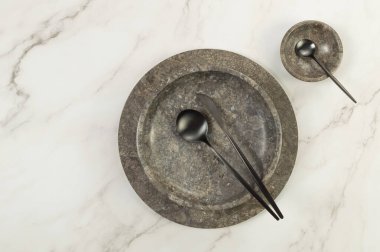 Kahverengi mermer tepsi, tabak, kase ve siyah çatal bıçak takımları beyaz mermer arka planda. Yemek sunumu, tabaklar, taş tepsi. Uzayı kopyala, düz yat.