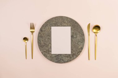 Kahverengi mermer plaka, altın çatal bıçak takımı ve pembe arka planda pembe kart. Yemek sunumu, taş tepsi. Tablo ayarı, kopyalama alanı, düz uzanma.