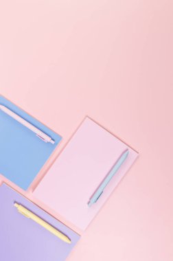 Pembe, mor ve mavi arkaplanlı defterlerin üst görüntüsü. Pembe, sarı ve mavi kalemler, okul, ofis kağıdı. Düz yat, boşluğu kopyala.