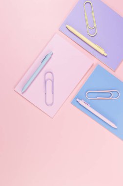 Pembe, mor ve mavi arkaplanlı defterlerin üst görüntüsü. Pembe, sarı ve mavi kalemler, ataçlar, okul, ofis kağıdı. Düz yat, boşluğu kopyala.
