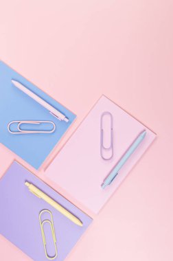 Pembe, mor ve mavi arkaplanlı defterlerin üst görüntüsü. Pembe, sarı ve mavi kalemler, ataçlar, okul, ofis kağıdı. Düz yat, boşluğu kopyala.