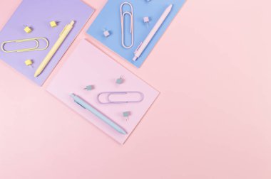 Pembe, mor ve mavi arkaplanlı defterlerin üst görüntüsü. Renkli kalemler, ataçlar, raptiyeler, okul, ofis kağıdı. Düz yat, boşluğu kopyala.