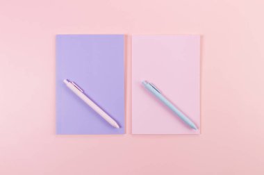 Pembe arka plandaki pembe ve mor defterlerin üst görüntüsü. Pembe ve mavi kalemler, okul, ofis kağıdı. Düz yat, boşluğu kopyala.