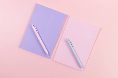 Pembe arka plandaki pembe ve mor defterlerin üst görüntüsü. Pembe ve mavi kalemler, okul, ofis kağıdı. Düz yat, boşluğu kopyala.