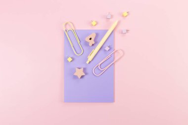 Pembe arka planda mor defterin üst görüntüsü. Ataç, kalem, numara, şekil ve iğne. Okul, ofis duvar kağıdı. Düz yat, boşluğu kopyala.