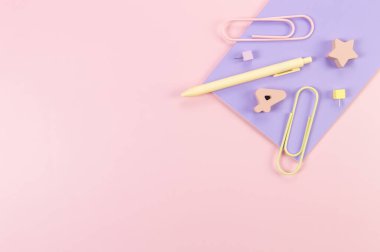 Pembe arka planda mor defterin üst görüntüsü. Ataç, kalem, numara, şekil ve iğne. Okul, ofis duvar kağıdı. Düz yat, boşluğu kopyala.