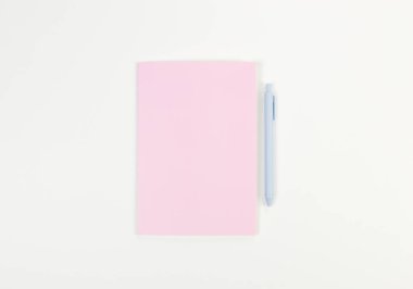 Pembe defterin üst görüntüsü, beyaz arka planda mavi kalem. Okul, ofis duvar kağıdı. Düz yat, boşluğu kopyala.