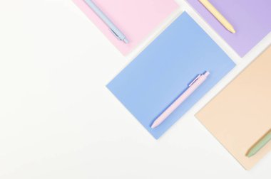 Beyaz arka planda pembe, mor, mavi ve bej renkli defterlerin üst görüntüsü. Renkli kalemler, okul, ofis kağıdı. Düz yat, boşluğu kopyala.