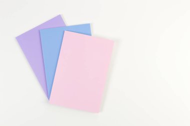 Beyaz arka planda pembe, mor ve mavi defterlerin üst görüntüsü. Okul, ofis duvar kağıdı. Düz yat, boşluğu kopyala.