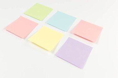 Beyaz arkaplandaki renkli yapışkan notların üst görünümü. Okul, ofis duvar kağıdı. Düz yat, boşluğu kopyala.