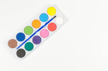 Beyaz arka planda suluboya ve boya fırçasının üst görüntüsü. Resim, sanat, kopyalama alanı, düzlük.