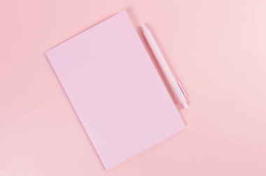 Pembe defterin üst görüntüsü, pembe arka planda pembe kalem. Okul, ofis duvar kağıdı. Düz yat, boşluğu kopyala.