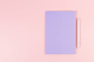 Mor defterin üst görüntüsü, pembe arka planda pembe kalem. Okul, ofis duvar kağıdı. Düz yat, boşluğu kopyala.