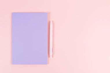 Mor defterin üst görüntüsü, pembe arka planda pembe kalem. Okul, ofis duvar kağıdı. Düz yat, boşluğu kopyala.