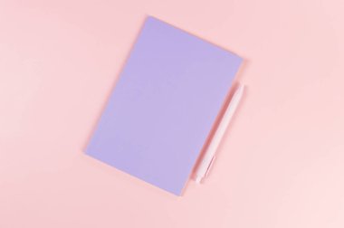 Mor defterin üst görüntüsü, pembe arka planda pembe kalem. Okul, ofis duvar kağıdı. Düz yat, boşluğu kopyala.