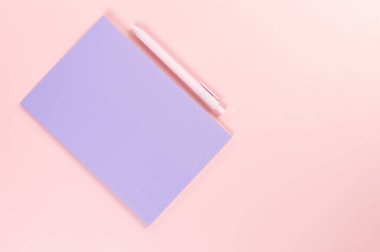 Mor defterin üst görüntüsü, pembe arka planda pembe kalem. Okul, ofis duvar kağıdı. Düz yat, boşluğu kopyala.