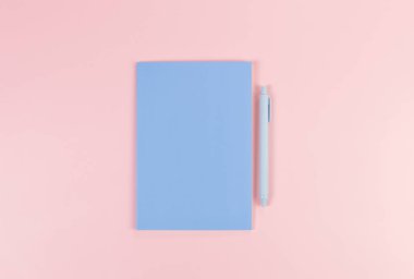 Mavi defterin üst görüntüsü, pembe arka planda mavi kalem. Okul, ofis duvar kağıdı. Düz yat, boşluğu kopyala.