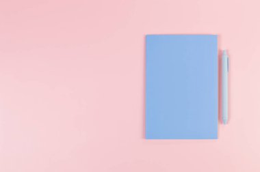 Mavi defterin üst görüntüsü, pembe arka planda mavi kalem. Okul, ofis duvar kağıdı. Düz yat, boşluğu kopyala.
