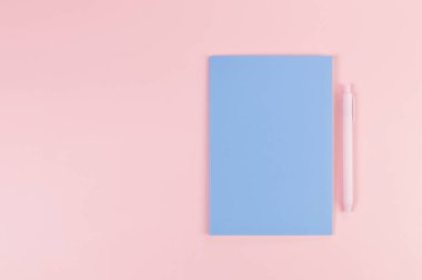 Mavi defterin üst görüntüsü, pembe arka planda pembe kalem. Okul, ofis duvar kağıdı. Düz yat, boşluğu kopyala.