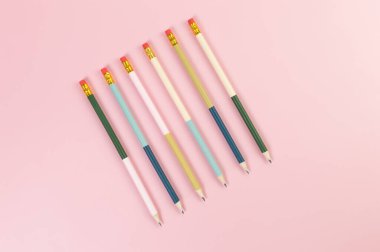 Pembe arka planda renkli kalemlerin üst görüntüsü. Okul, ofis, duvar kâğıdı. Düz yat, boşluğu kopyala.