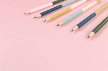 Pembe arka planda renkli kalemlerin üst görüntüsü. Okul, ofis, duvar kâğıdı. Düz yat, boşluğu kopyala.