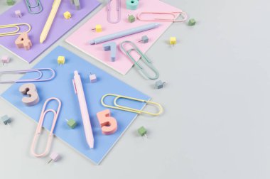 Gri arkaplanda pembe, mor ve mavi defterlerin üst görüntüsü. Renkli kalemler, ataçlar, numaralar ve iğneler. Okul, ofis duvar kağıdı. Düz yat, boşluğu kopyala.