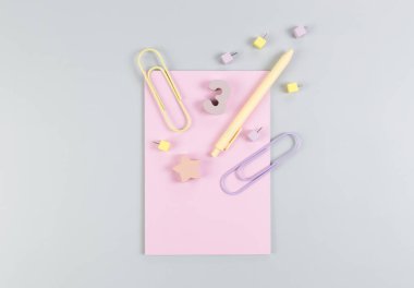 Gri arkaplandaki pembe defterin üst görüntüsü. Ataç, kalem, numara, şekil ve iğne. Okul, ofis duvar kağıdı. Düz yat, boşluğu kopyala.