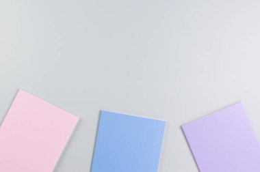 Gri arkaplanda pembe, mor ve mavi defterlerin üst görüntüsü. Okul, ofis duvar kağıdı. Düz yat, boşluğu kopyala.