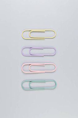 Gri arkaplanda renkli ataçların üst görünümü. Okul, ofis duvar kağıdı. Düz yat, boşluğu kopyala.