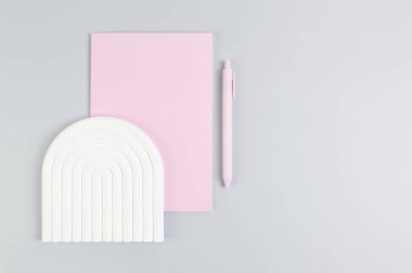 Pembe defterin üst görüntüsü, pembe kalem, gri arka planda beyaz kemer tepsisi. Okul, ofis duvar kağıdı. Düz yat, boşluğu kopyala.