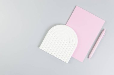 Pembe defterin üst görüntüsü, pembe kalem, gri arka planda beyaz kemer tepsisi. Okul, ofis duvar kağıdı. Düz yat, boşluğu kopyala.
