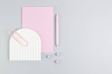 Pembe defter, pembe kalem, ataç, raptiyeler, gri arka planda beyaz kemer tepsisi. Okul, ofis duvar kağıdı. Düz yat, boşluğu kopyala.