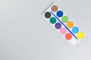 Gri arkaplanda suluboya ve boya fırçasının üst görüntüsü. Resim, sanat, kopyalama alanı, düzlük.