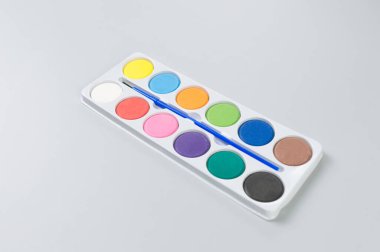 Gri arkaplanda suluboya ve boya fırçasının üst görüntüsü. Resim, sanat, kopyalama alanı, düzlük.