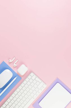 Beyaz klavye, fare, dokunmatik ped, kulaklık kutusu, pembe arka planda kalem. Mor ve mavi defterler, modern ofis, okul. Düz yat, boşluğu kopyala.