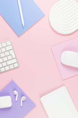 Beyaz klavye, fare, dokunmatik ped, kulaklık kutusu, pembe arka planda kalem. Mor, pembe ve mavi defterler, modern ofis, okul. Beyaz kemer tepsisi, düz konum, kopyalama alanı.