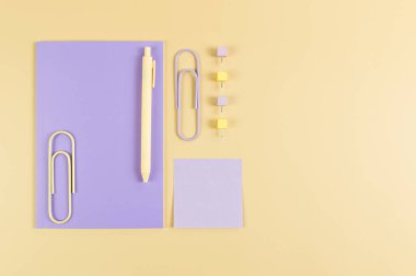 Sarı arkaplanda mor defterin üst görüntüsü. Yapışkan not, ataç, kalem ve iğne. Okul, ofis duvar kağıdı. Düz yat, boşluğu kopyala.